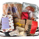 Basket full of Granville Island goods, including coffee, cheese, toffee, lemon squares, tea, charcuterie and bread