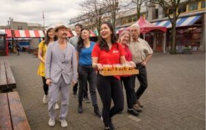 a group of 6 people follow the foodie tour guide with a tray of beer