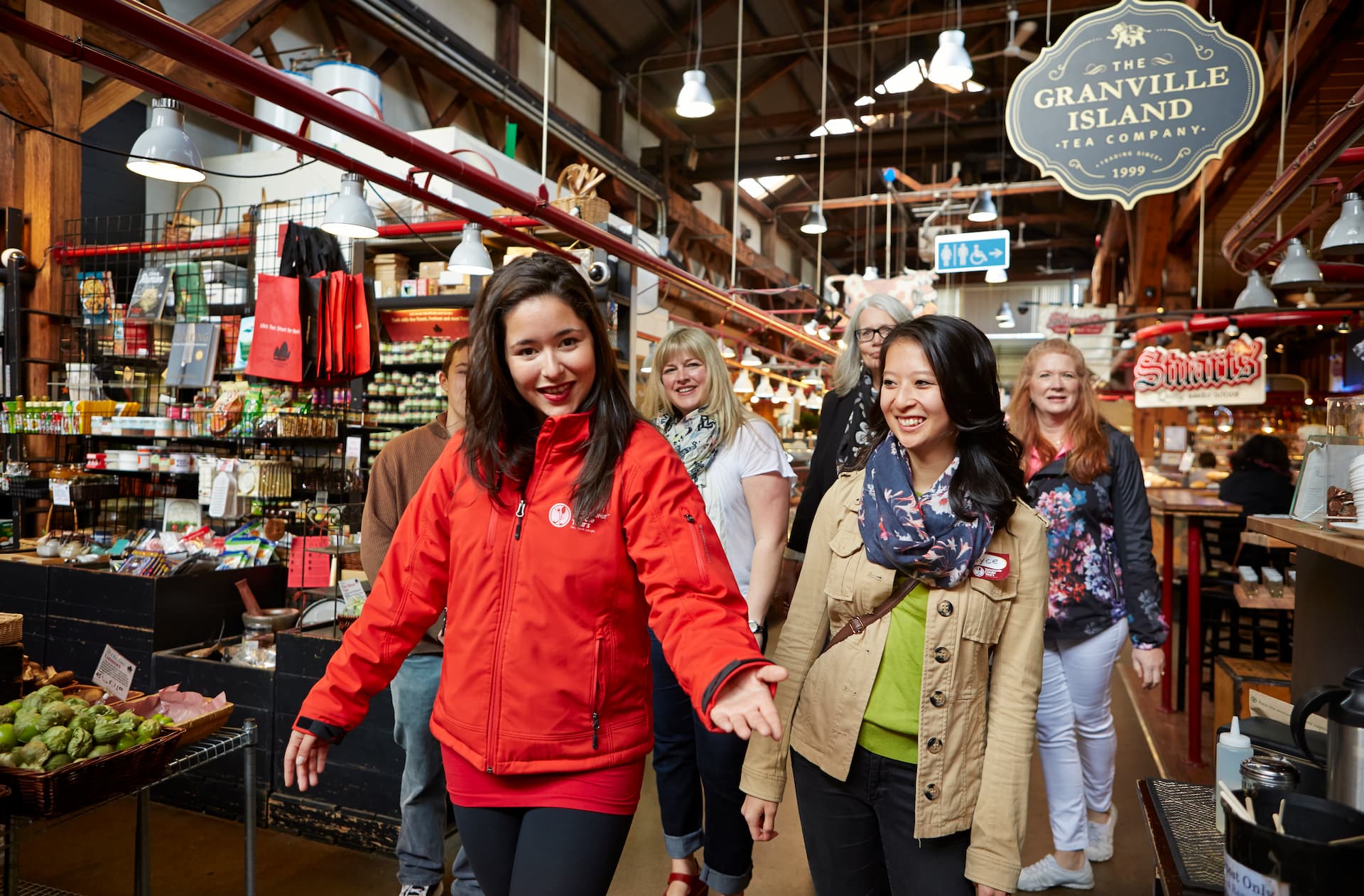 A guide in a red jacket leads a tour group through the market