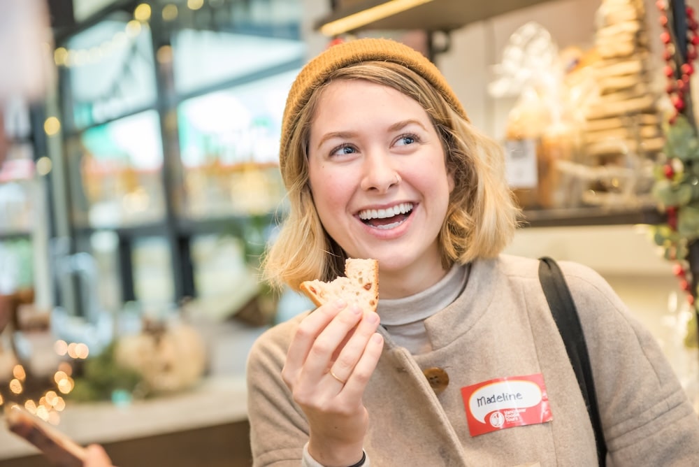 A smiling woman holding a half-eaten piece of a traditional Christmas cookie