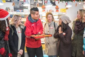 A Vancouver Foodie Tours guide holding a tray of freshly-baked doughnuts, ready to share them with his group