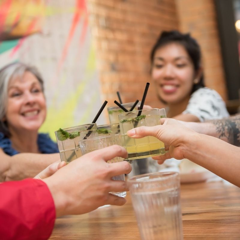 a group of foodie tour guests cheers with big smiles on their faces