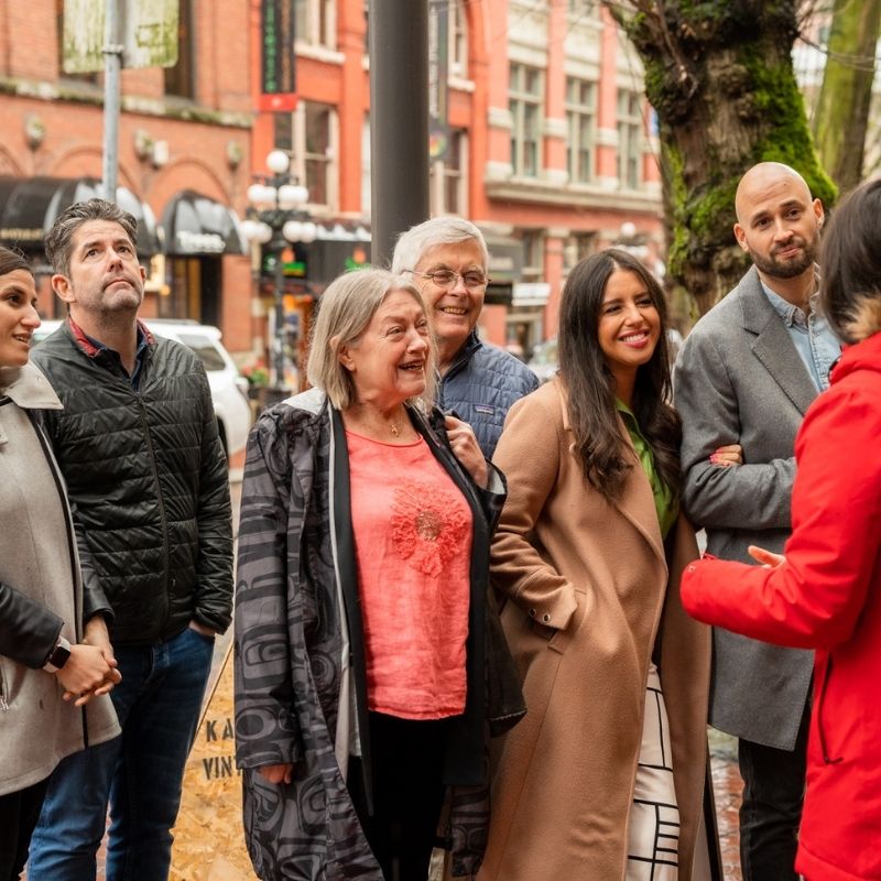 a Vancouver Foodie Tour group smiles as they listen to the guide. a great group photo op