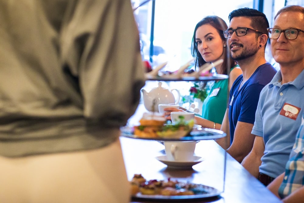 a corporate team sitting at a table and listening to a local business owner sharing their insights about the cuisine and culture of Vancouver during an inspiring team-building activity