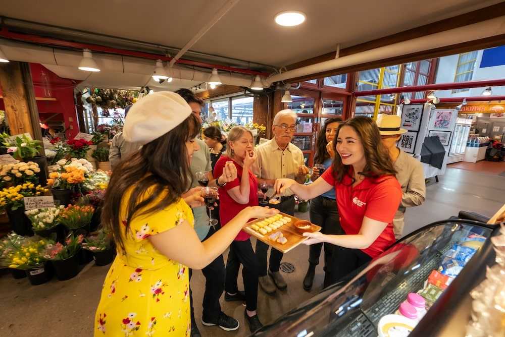 a tour guide passing around a platter with cheeses and cold-cuts at one of the stops during a team outing at the marketplace