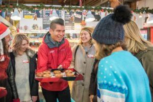 A Vancouver Foodie Tours guide holding a tray of donuts ready to share with the corporate team members on his tour