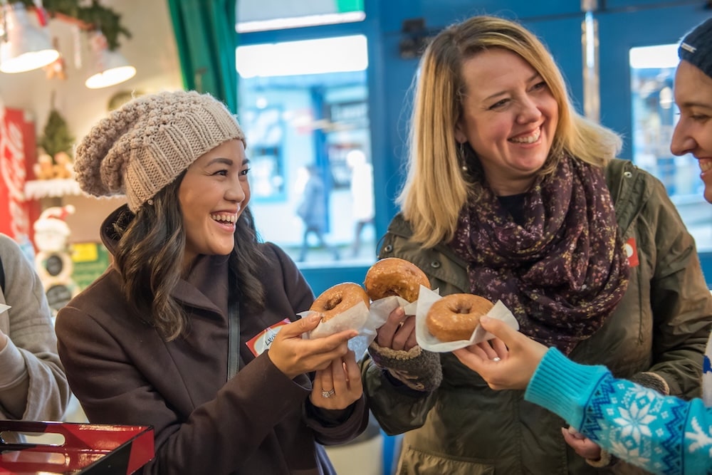 guests on a scavenger hunt in the Granville Island marketplace enjoying doughnuts