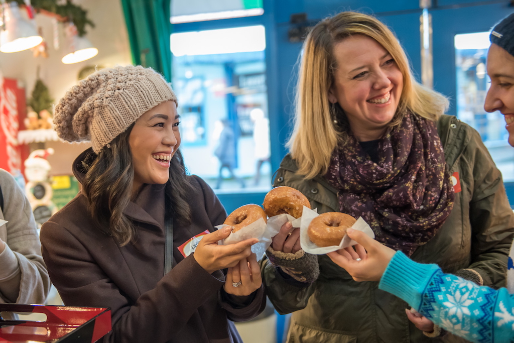 guests on a scavenger hunt in the Granville Island marketplace enjoying doghnuts