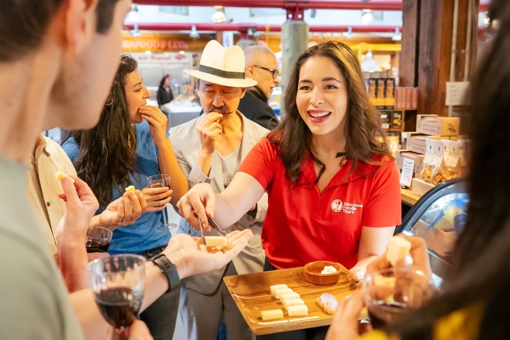 A Vancouver Foodie Tours guide handing out food tastings from a wooden platter to her guests