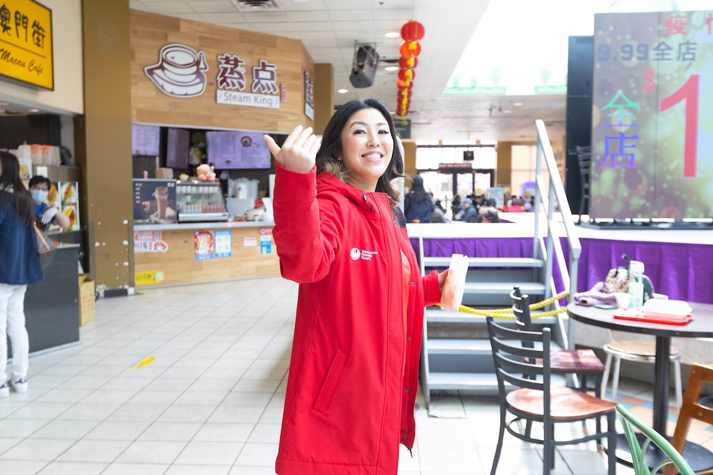 a tour guide from Vancouver Foodie Tours waving her hand at her group of guests to follow her for an unforgettable team experience