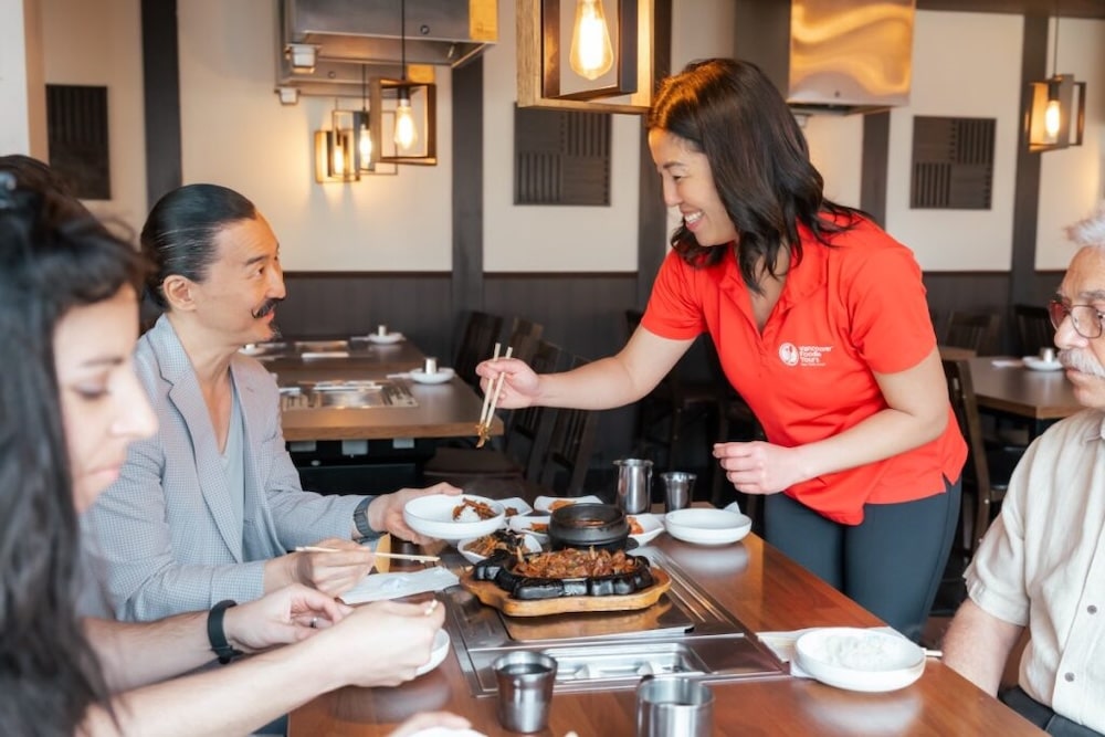 a Vancouver Foodie Tours guide in a red shirt serving asian food to her guests on a food tour