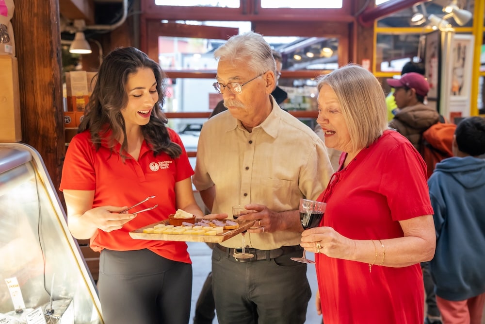 a helpful tour guide offering a cheese platter to her guests on a food tour, ready to answer any of their questions and provide recommendations