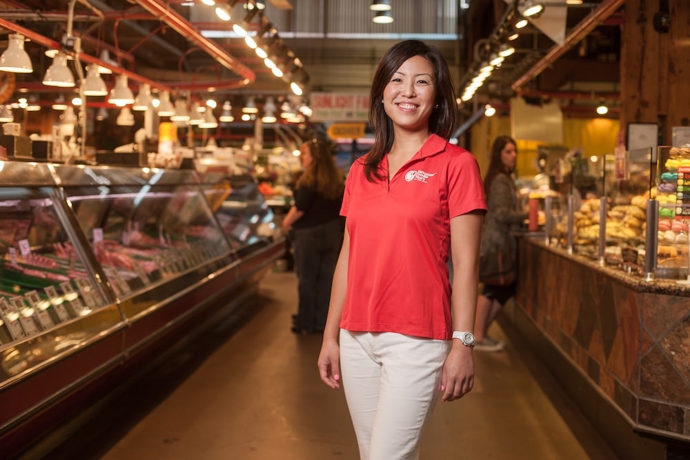 Michelle, the founder of Vancouver Foodie Tours, standing inside a marketplace in Vancouver ready to welcome travelers on her unique food tours