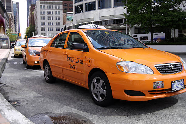 A taxi or ride-share vehicle dropping off passengers at the entrance to Granville Island