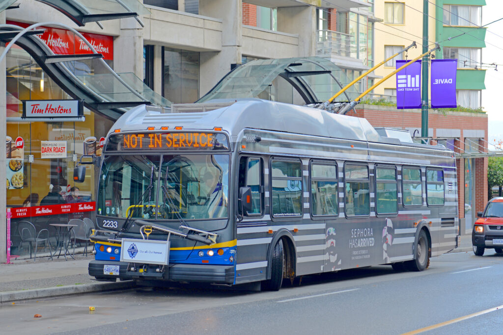 A TransLink #50 False Creek bus stopped at a bus stop on Granville Island, showing its accessibility for public transit.