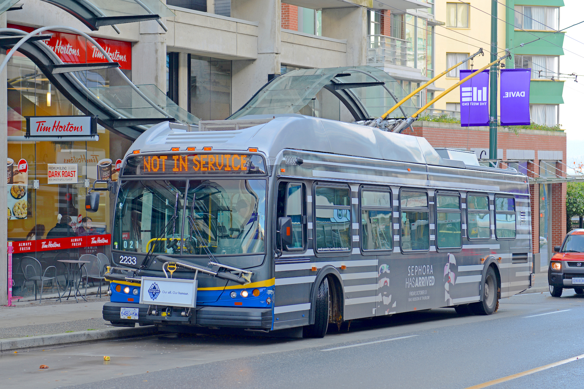 A TransLink #50 False Creek bus stopped at a bus stop on Granville Island, showing its accessibility for public transit.
