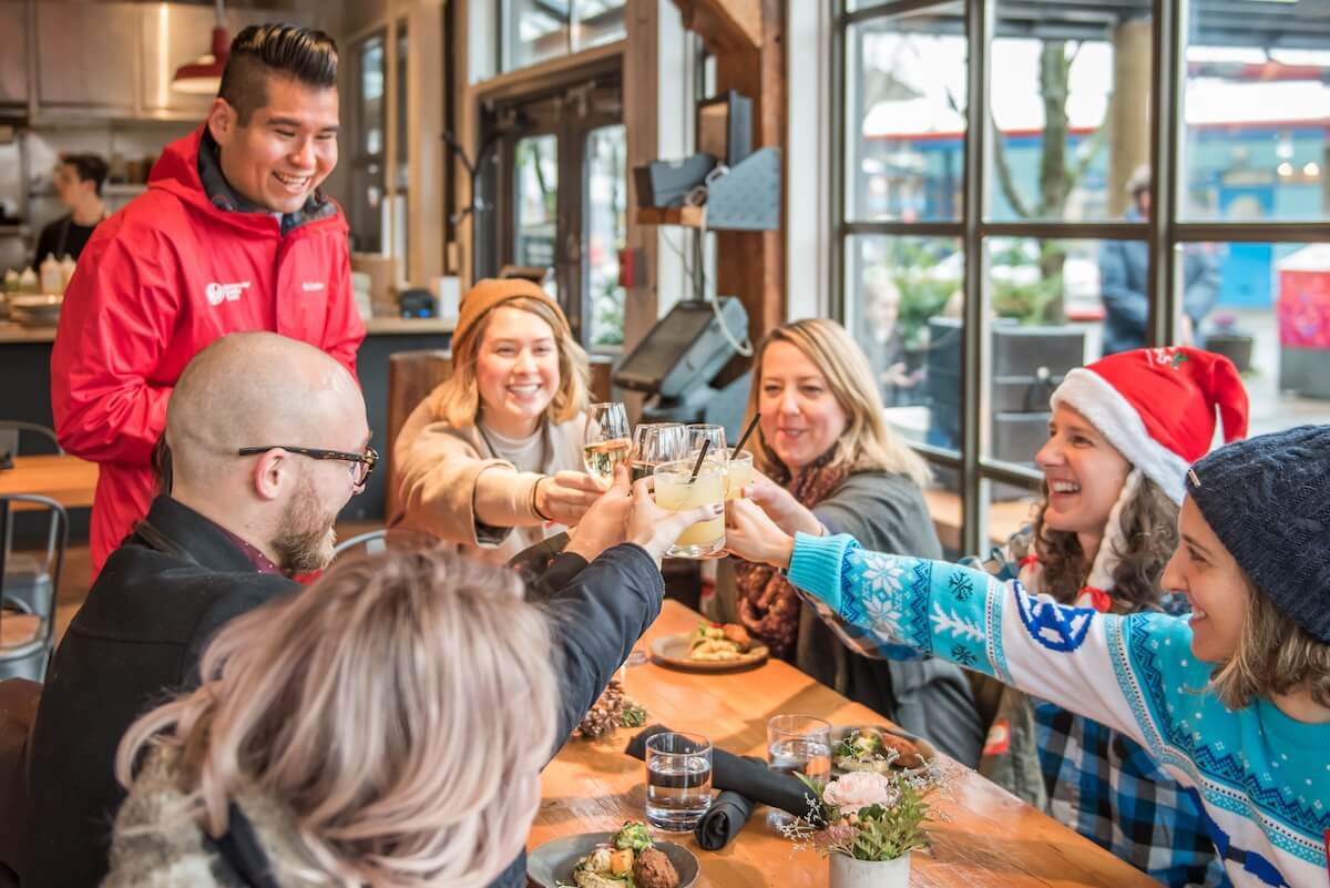 Team celebrating a staff Christmas party with drinks during a Vancouver Foodie Tours event