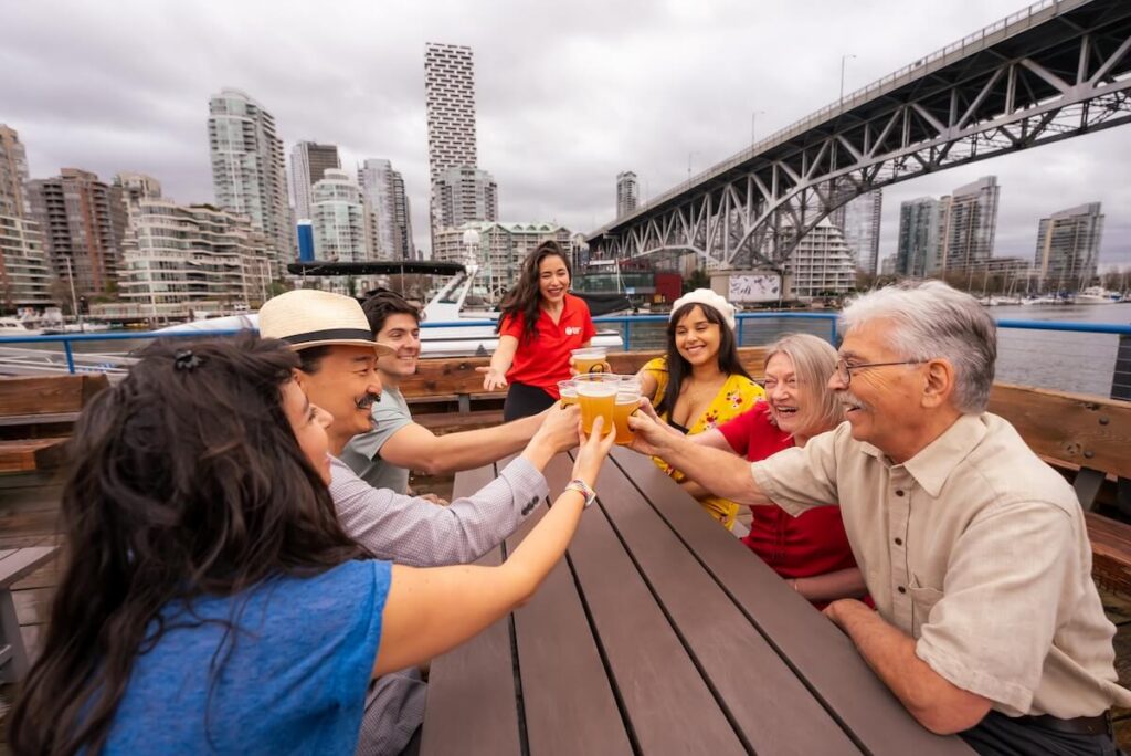 Corporate group raising drinks on a Vancouver waterfront staff party experience.
