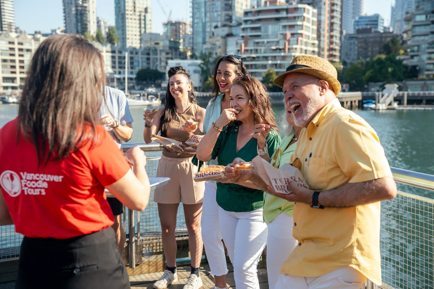 Guests enjoying a tasting with a Vancouver Foodie Tours guide on the Granville Island waterfront during the Granville Island Market Tour