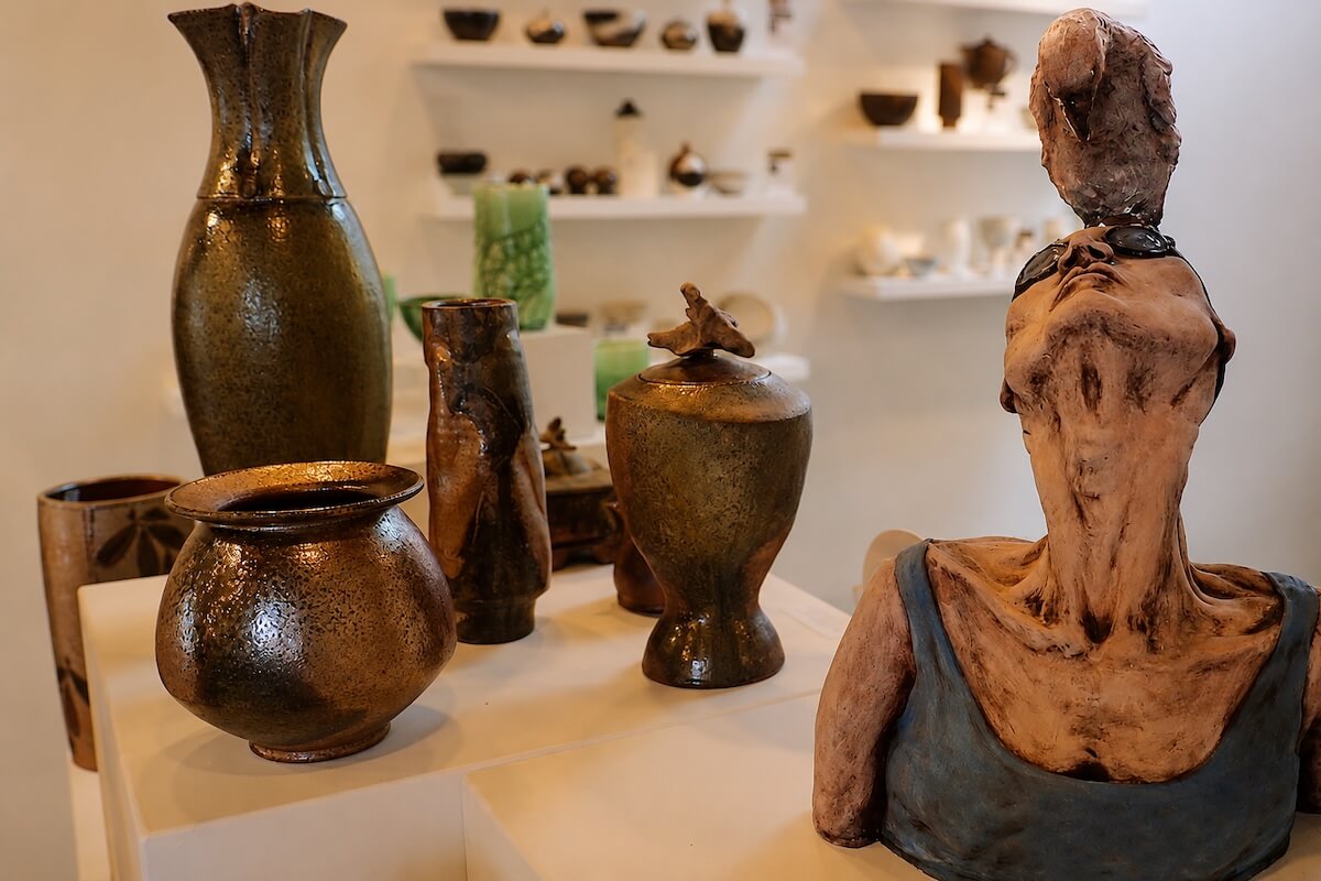 Handcrafted ceramic vessels and a figurative sculpture displayed inside an artisan gallery on Granville Island.