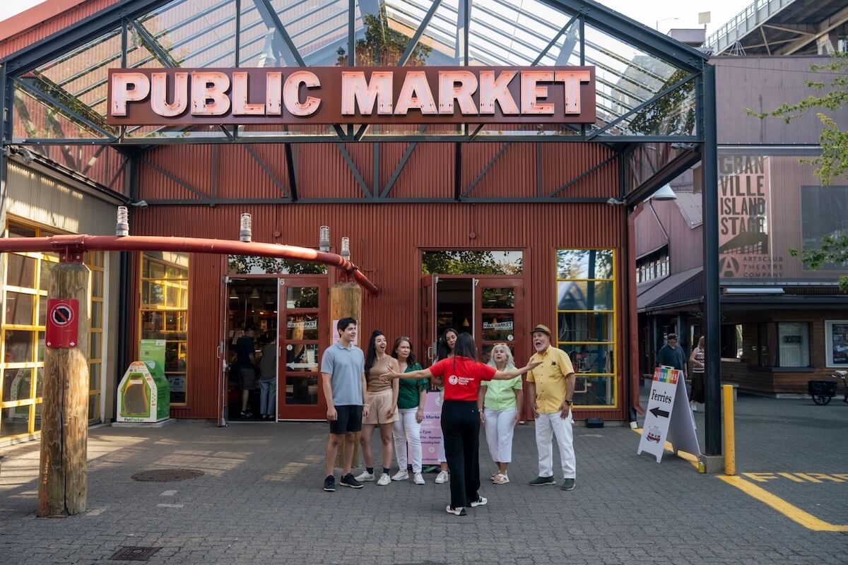 Vancouver Foodie Tours guide speaking to a small group outside the entrance to Granville Island Public Market.