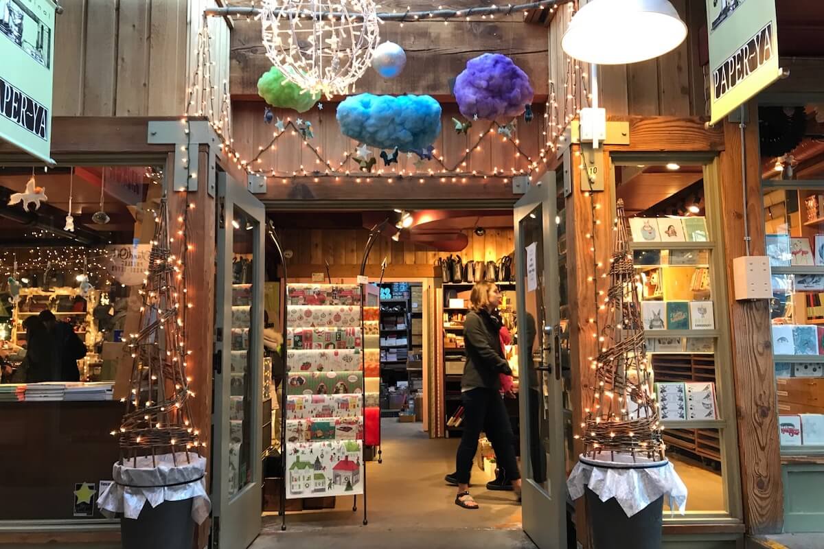 Entrance to Paper-Ya on Granville Island, decorated with string lights and colourful hanging clouds, with stationery and paper goods displayed inside.
