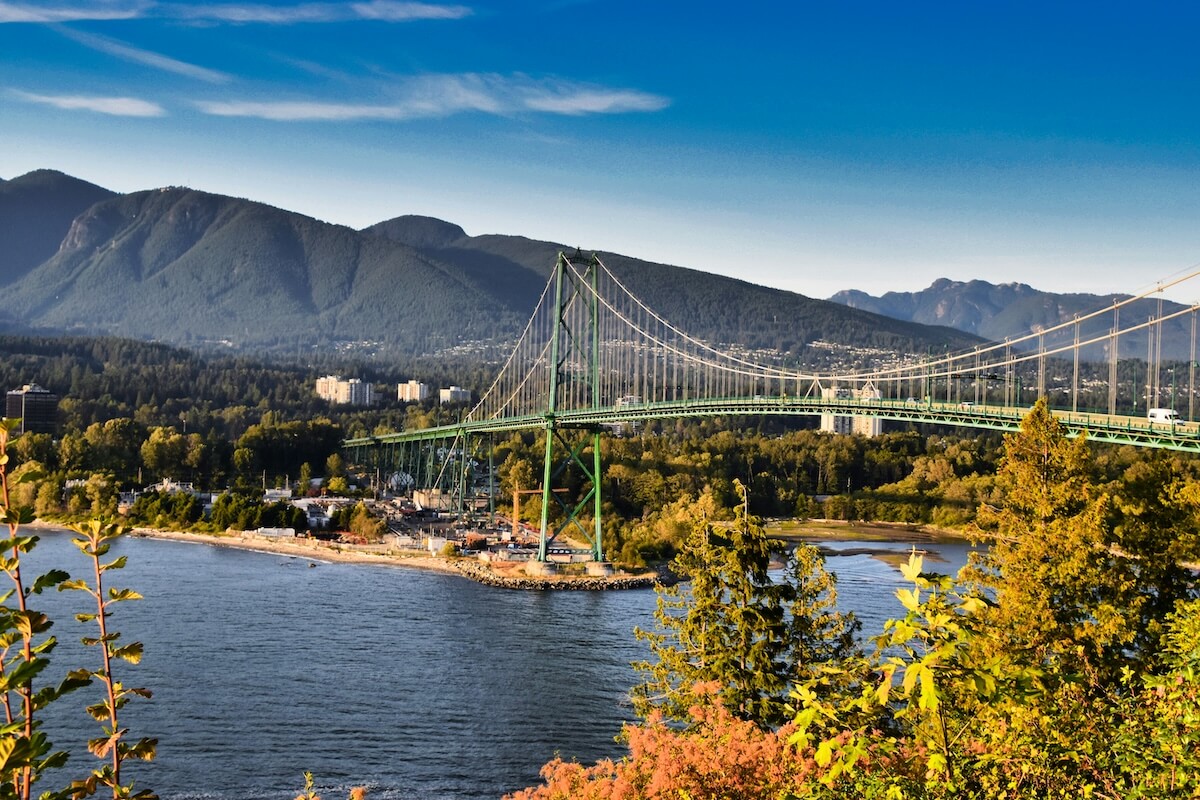 Lions Gate Bridge surrounded by green and early autumn foliage on a clear Vancouver day