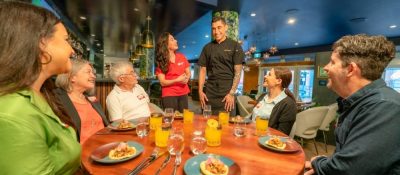 A corporate team of coworkers enhancing their team collaboration while seated at a round table together during a foodie group experience in Vancouver